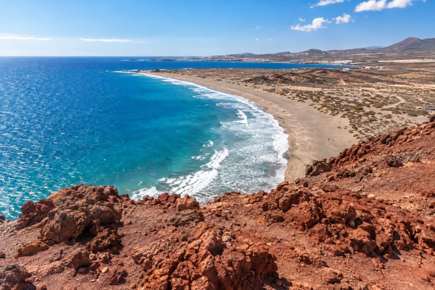 View from red volcanic rocks above the curving La Tejita beach and turquoise Atlantic