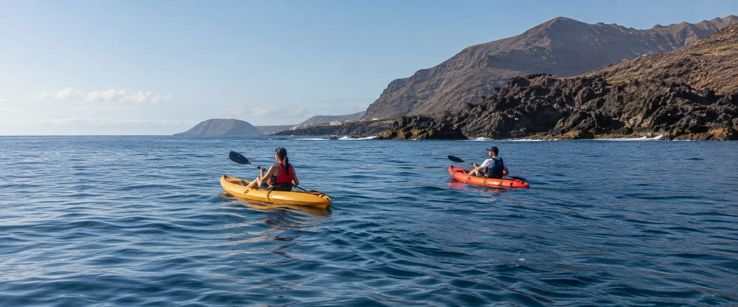 Sea kayakers crossing calm Atlantic water off the volcanic Palm-Mar coast in Tenerife